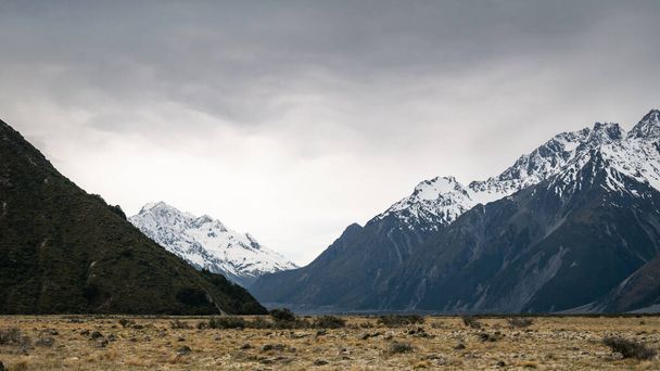 Blick auf das Alpental während des nahenden Sturms mit schneebedeckten Gipfeln im Hintergrund, aufgenommen im Aoraki Mt Cook National Park, Neuseeland - Foto, Bild
