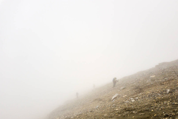 A turisták egy csoportja a ködön keresztül mászik fel a hegyre. Kiváló minőségű fénykép - Fotó, kép