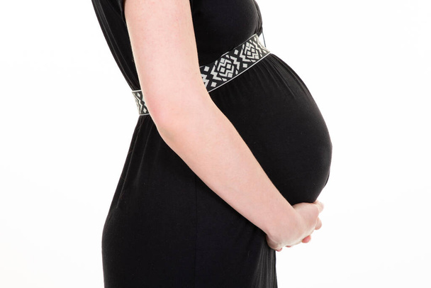 妊娠中女性おなかの体側プロフィールで黒ドレスビューで白の背景 - 写真・画像