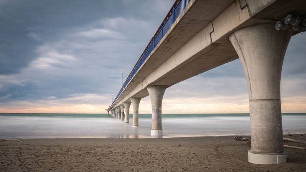 Píer de concreto maciço que leva ao horizonte cercado pelo oceano. Longa exposição tiro feito em New Brighton Beach em Christchurch, Nova Zelândia - Foto, Imagem