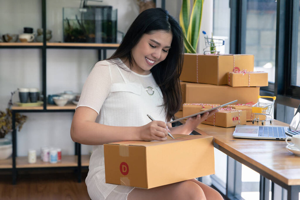 Succesvolle ondernemer zakenvrouw met online verkoop en Pakket verzending in haar eigen kantoor, voor te bereiden pakket doos van product voor levering aan de klant. - Foto, afbeelding