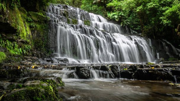 Beautiful cascade waterfall surrounded by forest. Shot made at Purakanui Falls in Catlins Forest Park, New Zealand - Photo, Image