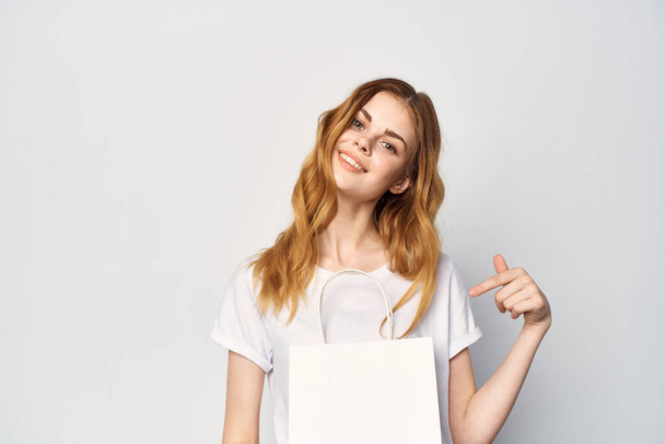donna in bianco t-shirt pacchetto in mani regalo shopping luce sfondo - Foto, immagini