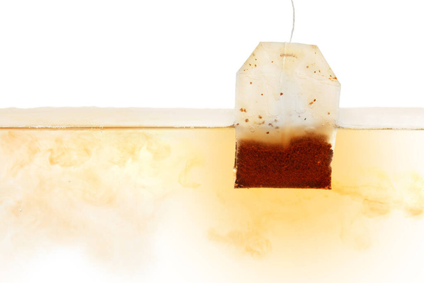 Dipping of tea bag into hot water against white background - Photo, image