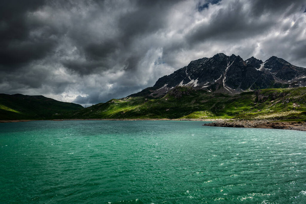 See in den italienischen Alpen mit Gewitterwolken am Himmel und Sonnenstrahlen auf dem Wasser - Foto, Bild