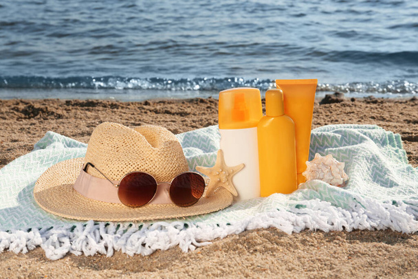 Sun protection products and beach accessories on blanket near sea - Фото, изображение