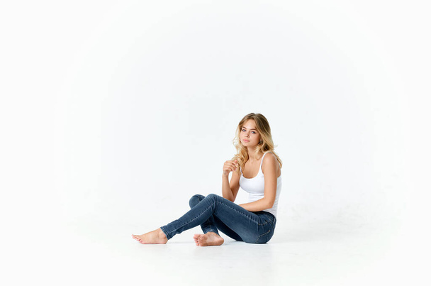 симпатичная блондинка с волосами, сидя на полу на изолированном фоне - Фото, изображение