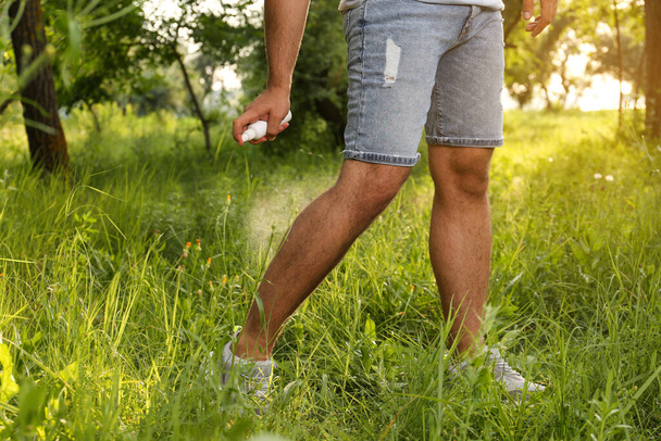Man applying insect repellent on leg in park, closeup. Tick bites prevention - Фото, зображення