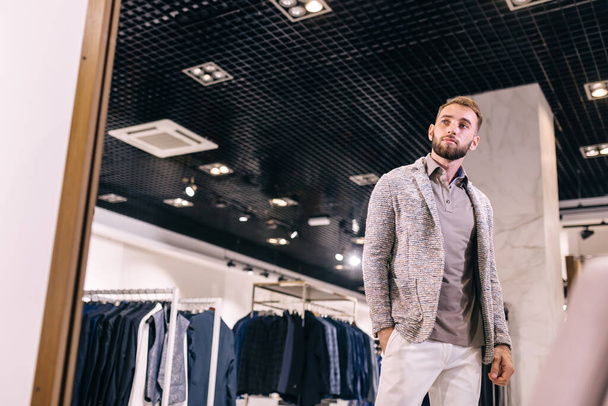 Bonito homem experimentando roupas elegantes em uma loja - Foto, Imagem