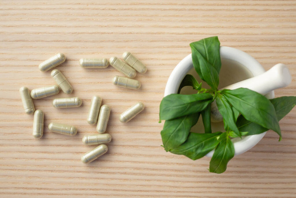 Herbal medicine capsules with Andrographis paniculata leaf on wood table - Fotó, kép
