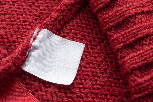 Etiqueta de ropa de lavado en blanco sobre fondo de textura de tela de punto rojo - Foto, imagen