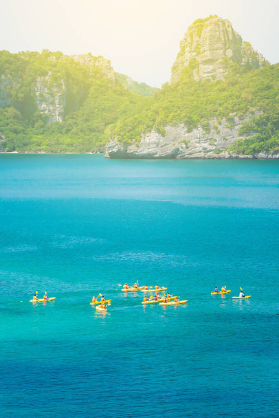 Gökyüzü manzaralı bir grup turist, arka planda yeşil adayla mavi denizde kayak yapıyor. Güneşli yazda tropikal adalarda kano yapmak. Mu Koh Ang Tanga Ulusal Parkı, Surat Thani, Tayland. Kanoya odaklan.. - Fotoğraf, Görsel