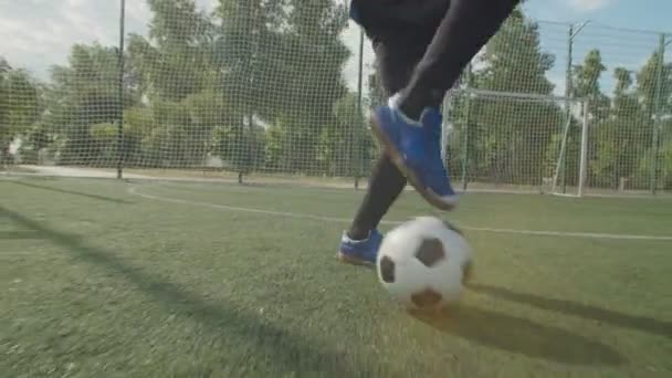 Γκρο πλαν μπροστινή όψη των ποδιών ποδοσφαιριστή σε μπότες ποδοσφαίρου με μπάλα - Πλάνα, βίντεο