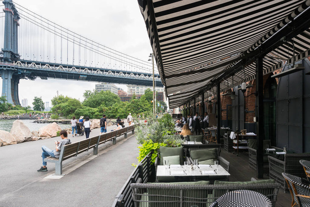 Nova Iorque, EUA - 6 de agosto de 2019: As pessoas comem e conversam enquanto estão sentadas em um dos muitos clubes do Brooklin bridge park durante um dia nublado. - Foto, Imagem