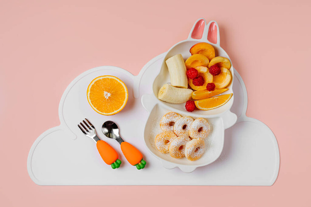 Colazione per bambini. Piatto carino a forma di coniglietto con ciambelle e frutta. Idea alimentare per bambini. - Foto, immagini