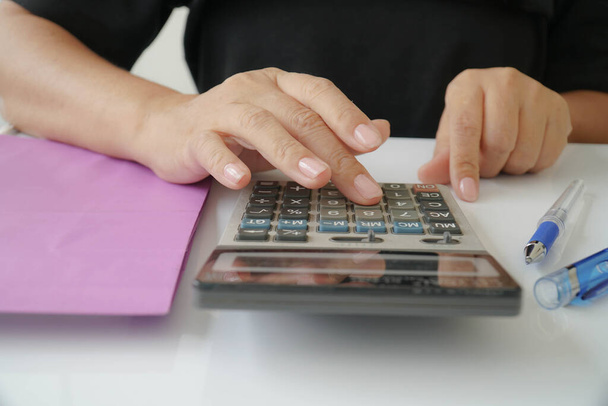 Zakenvrouw gebruikt rekenmachines om het bedrijfsbudget te berekenen en te analyseren. - Foto, afbeelding