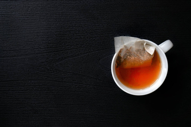 Чайные пакетики в белой кофейной кружке (Чайные пакетики выделяют миллиарды микропластиков и нанопластиков в чай) - Фото, изображение