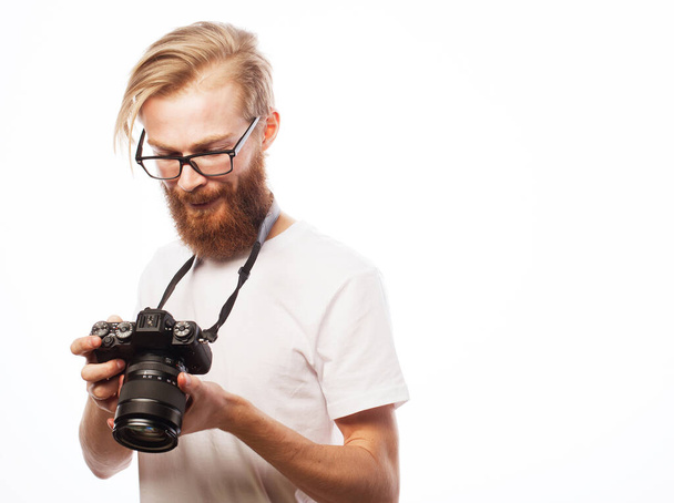 Young bearded photographer wearing glasses looking at photos on the camera screen over white background - Foto, imagen