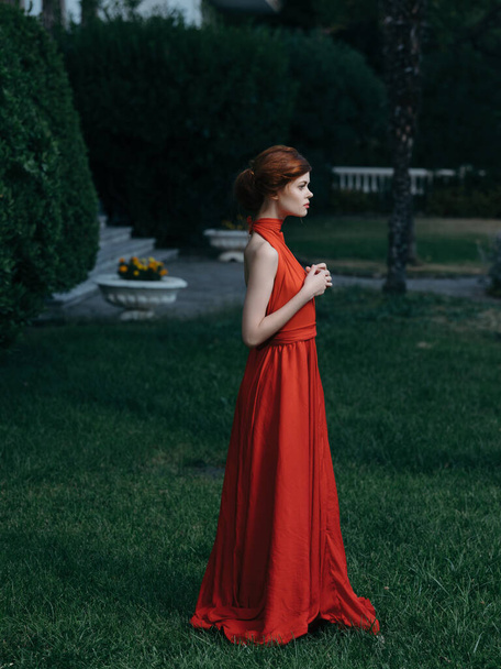 mulher perto de arbusto em vestido vermelho e decoração de jardim de fadas - Foto, Imagem