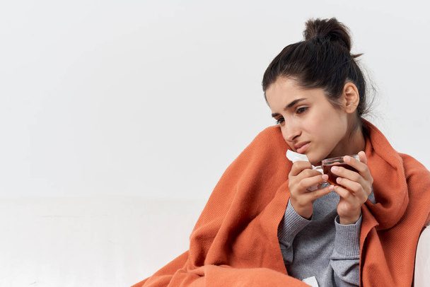 woman with a cup of tea hiding behind a blanket at home cold infection - Foto, Imagen