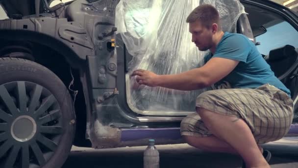 painter who seals the holes of the car and other body elements with paint tape, - Footage, Video
