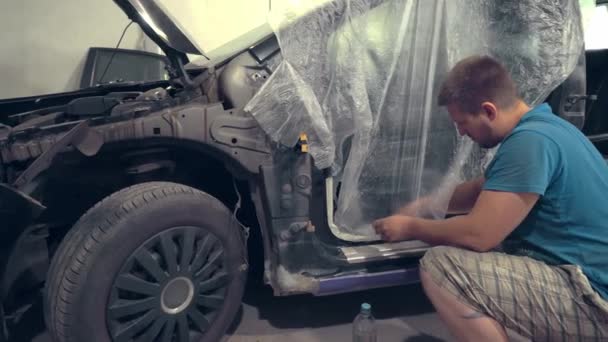 Maler, der die Löcher des Autos und anderer Karosserieteile mit Farbklebeband versiegelt, - Filmmaterial, Video