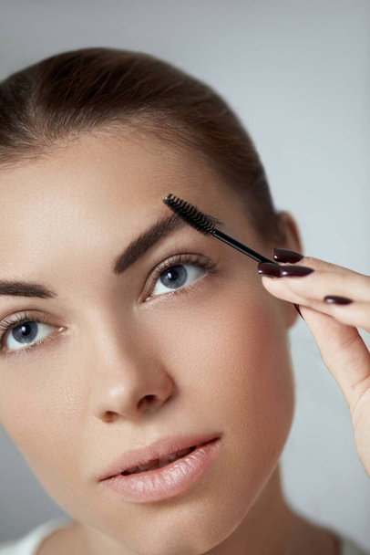 Young beautiful woman correcting shape of eyebrows. Contouring Eyebrow makeup .  - Fotó, kép