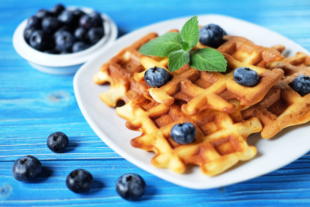 Traditional belgian waffles with fresh berrys and sugar powder on white plate, blue wooden background. Flat lay, top view, copy space. - Valokuva, kuva