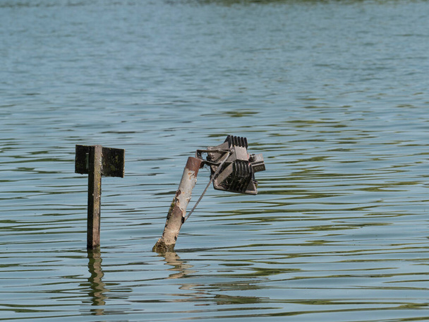 Lámpara rota se coloca en el agua con un cable eléctrico expuesto - Foto, Imagen