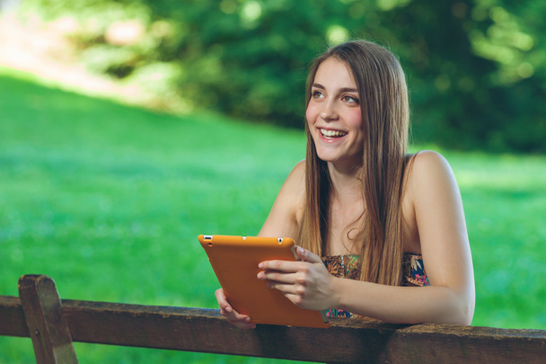 gyönyörű fiatal nő ül a padon, Park, tabletta - Fotó, kép