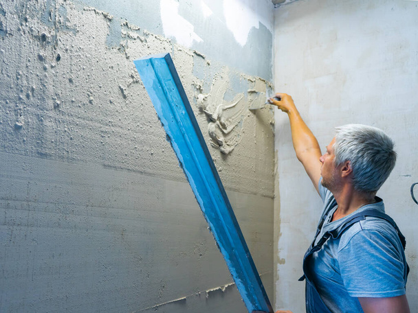 Applying plaster putty to the wall using a aluminum paver screed - Φωτογραφία, εικόνα