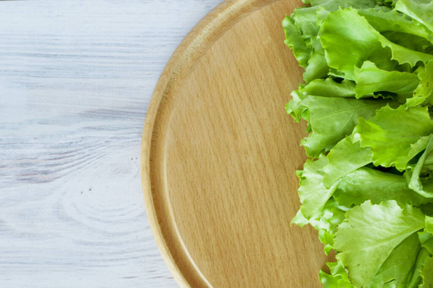 fresh green lettuce salad rests on a wooden board - Photo, image