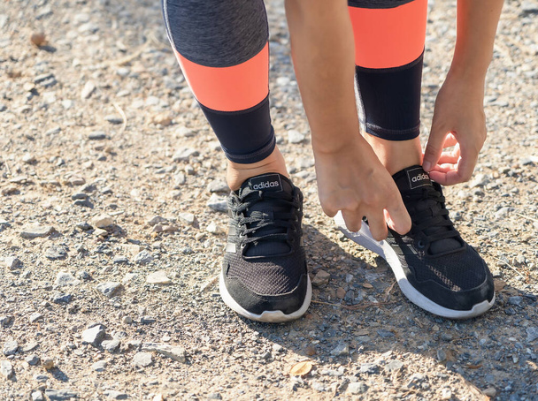 タイのスファン・ブリ- 2021年7月24日:路上に立つ靴と脚の女性の靴を結ぶ手。陸上競技タイの公園で女性のジョギングやトレーニング.  - 写真・画像
