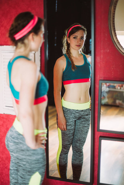 Profile pose of a fit woman looking in the mirror  - Foto, Bild