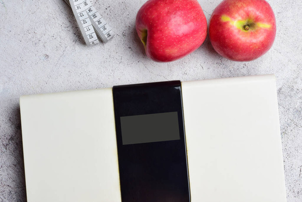 Concepto de salud, mantenimiento del peso adecuado y buena nutrición. Escala digital y dos manzanas, junto con una cinta métrica. Copiar espacio. - Foto, imagen