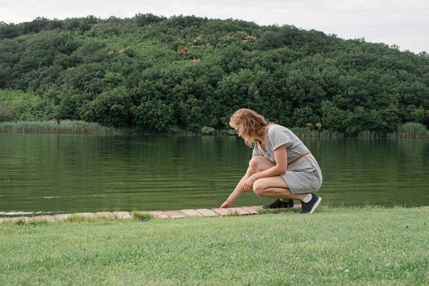 Φύση και ταξιδιωτική έννοια. γυναίκα κάθεται κοντά στη λίμνη - Φωτογραφία, εικόνα