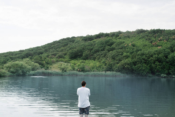 Concepto de naturaleza y viajes. Vista trasera de un hombre de pie cerca del lago - Foto, Imagen