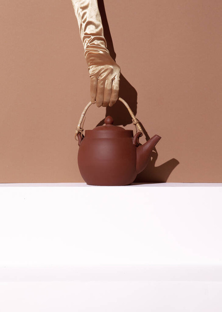 Hand holding Clay teapot minimal still life scene. Winter warm holiday seasonal time  wallpaper - Foto, Bild