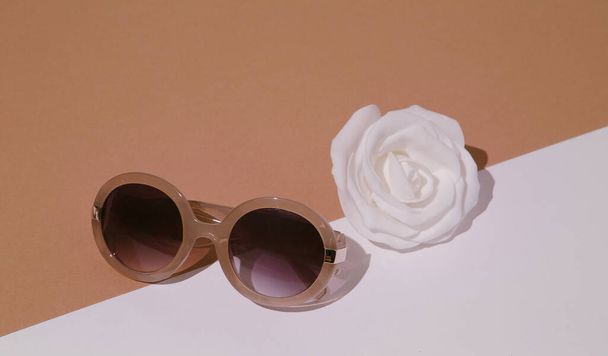Minimal fashion still life scene. Trendy accessory sunglasses and roses in white beige space. Shopping and sale concept. Stylish details in look - Foto, imagen