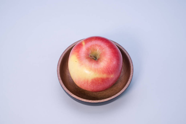 A red apple on wooden plate isolated on a white background with free space for text - Fotoğraf, Görsel