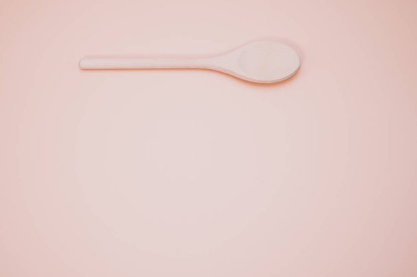 A wooden spoon isolated on a peach background with free space for text - Foto, immagini