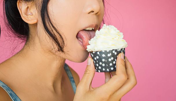 Cute Asian Girl Holds A Cupcake With Cream On Pink Background. - Φωτογραφία, εικόνα