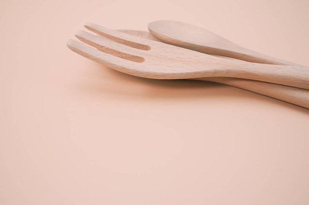 Een close-up shot van houten lepels en vork geïsoleerd op roze achtergrond - Foto, afbeelding