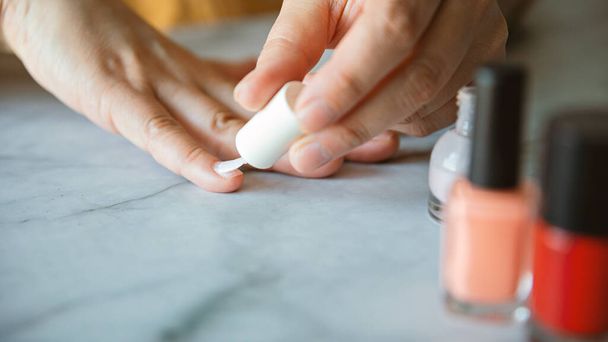 A closeup shot of a person painting their nails with a white polish - Foto, immagini