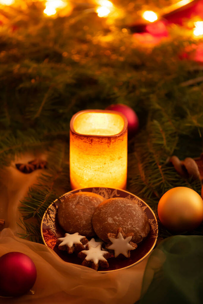 The decorations for Christmas - a glowing candle, cinnamon biscuits and shiny lights - Valokuva, kuva