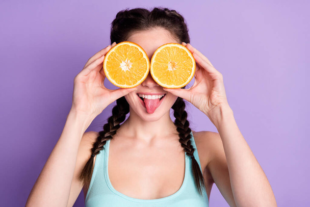 Photo of funky funny young woman cover eyes slice orange stick out tongue isolated on violet color background - Fotografie, Obrázek