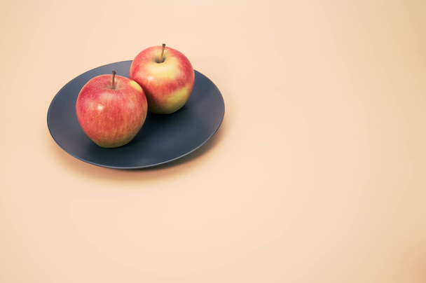 A closeup shot of fresh apples on a black round plate isolated on a pink background - Foto, imagen