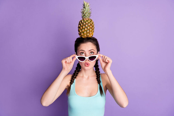 Portrait of attractive comic funny amazed girl holding on head ananas pout lips isolated over violet purple color background - 写真・画像