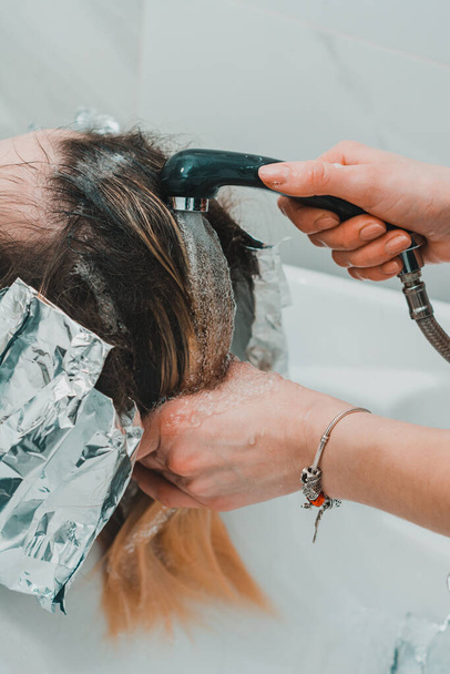理髪店の女性は髪を染め、髪を染めながら頭を洗う。新しい - 写真・画像