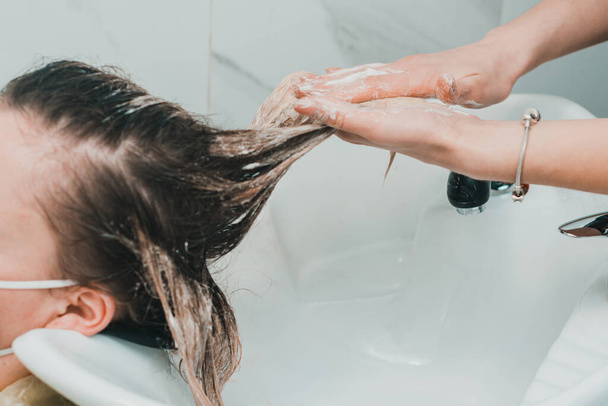 Il parrucchiere lava via la tintura per capelli, il lavaggio del cuoio capelluto e il processo di tintura dei capelli. nuovo - Foto, immagini